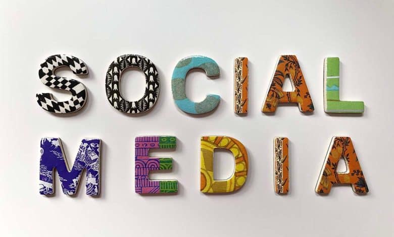 The phrase "social media" is spelled out with colorful, patterned letters, each uniquely designed with different textures and motifs, laid flat on a light grey background.