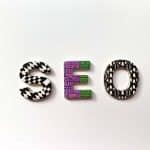 The word "seo" is formed with uniquely patterned letters on a plain white background. each letter is decorated distinctly with black and white geometric designs and vibrant purple and green abstract patterns.