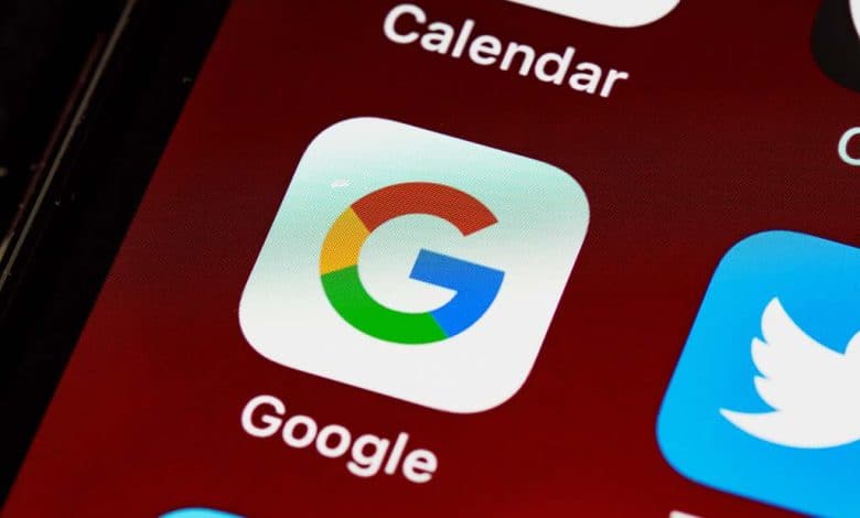 Close-up view of a smartphone screen displaying app icons, with a focus on the google app icon. the icon features google’s signature colorful letter "g". surrounding icons include the calendar and twitter apps.