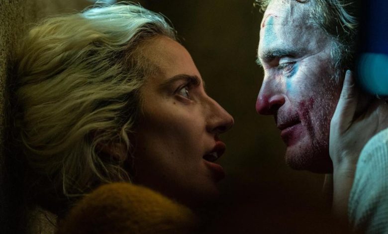 Close-up of a distressed man and a woman with intense expressions, facing each other under dim lighting in a scene reminiscent of "Joker 2". The man has bruises on his face and they both