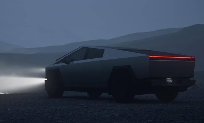 A futuristic, polygonal-designed Cybertruck with a matte finish, shown in a twilight misty setting with glowing red taillights, parked on a damp road surrounded by hazy,