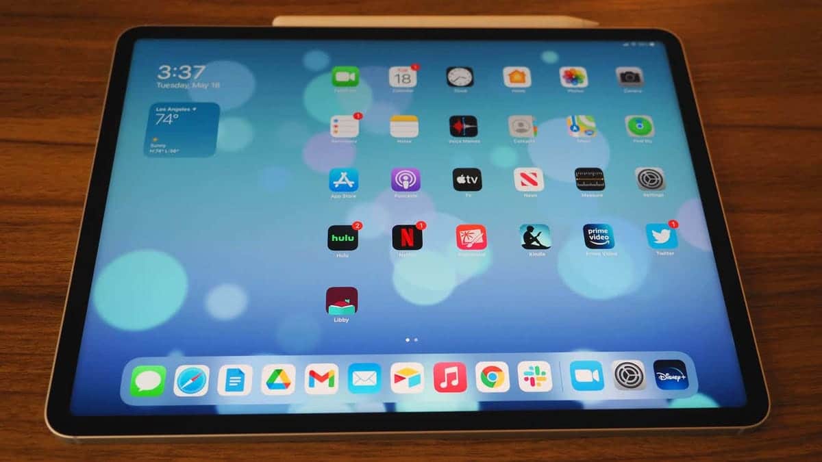 An iPad showing a vibrant screen with icons like messages, app store, Netflix, and Hulu, also displays time and weather.