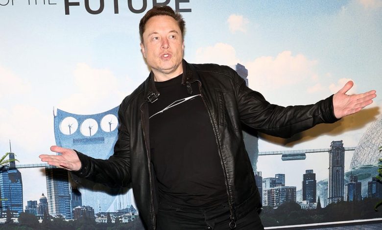Elon Musk stands in front of a graphical cityscape backdrop with a futuristic robot character, wearing a black leather jacket and gesturing outward with both hands, at the Tesla Robotaxi reveal event.