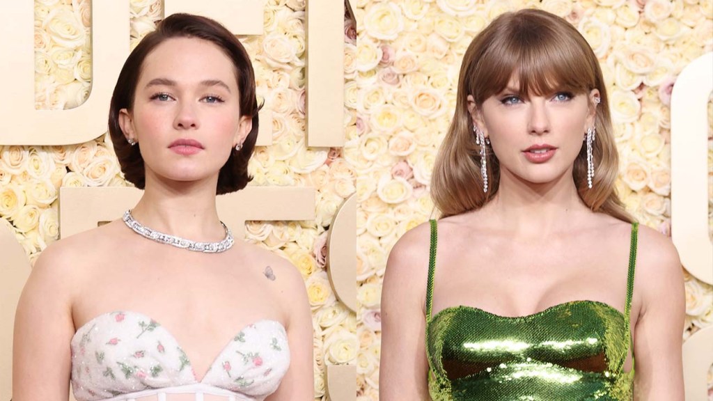 Two women posing in front of a flower wall; the person on the left, Cailee Spaeny, wears a floral corset gown and the person on the right, in awe of Taylor Swift,