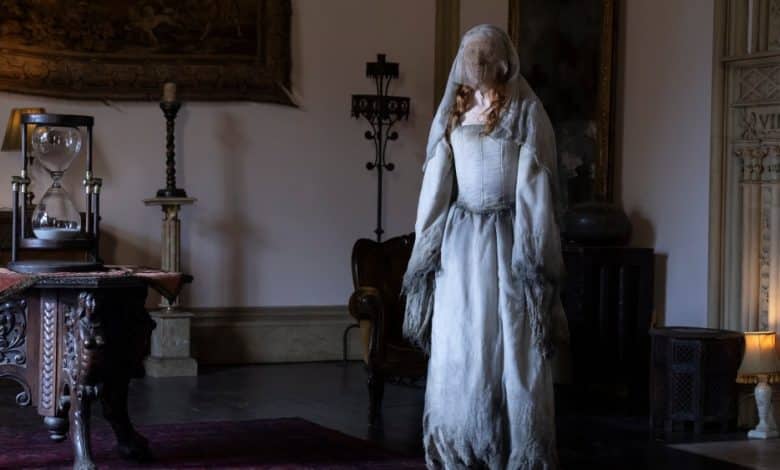 A ghostly figure in a tattered white dress stands in a dimly lit, elegant room, surrounded by antique furniture, a tapestry influenced by Eli Roth's VR Series 'The Faceless Lady