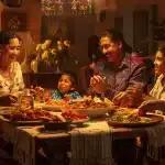 A joyful, multi-generational family gathers around a dining table filled with traditional dishes, celebrating the rich history of Latino and Hispanic Americans in a warmly lit room decorated with cultural ornaments. Laughter and
