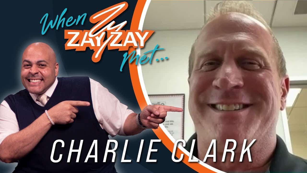Promotional image featuring two men, one pointing at the text "When Zay Zay Met..." above the name "Charlie Clark". The man on the left wears a vest and smiles, while the