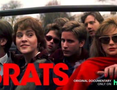 The Brat Pack, A group of young adults is crowded in an open-top car. They appear to be dressed in 1980s fashion. The text "BRATS" in bold, red letters is in the lower left. Below, it reads "ORIGINAL DOCUMENTARY ONLY ON hulu" in smaller white and green text. Trees and buildings are in the background.