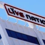 Sign of "live nation" atop a white architectural structure, featuring stylistic cut-outs and clean lines against a bright blue sky.