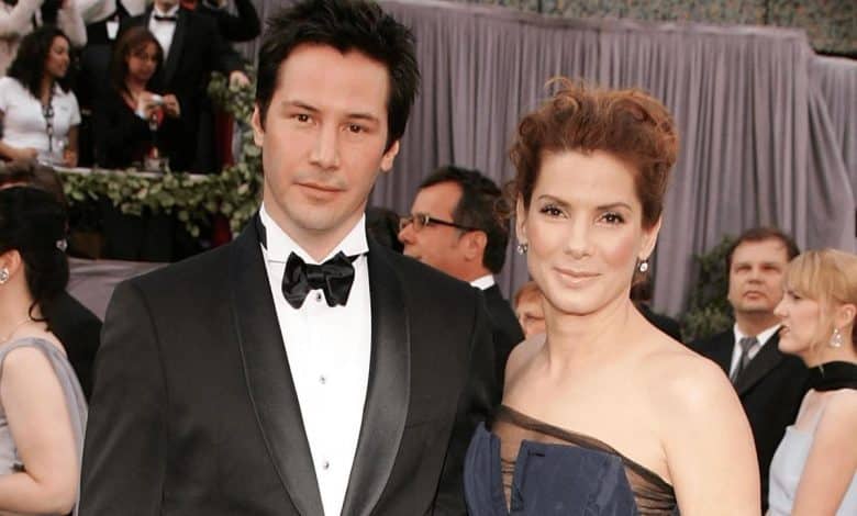 Two people on a red carpet. the man wears a black tuxedo with a bow tie, and the woman is in a strapless navy gown. they are standing close to each other, posing for the camera with slight smiles.