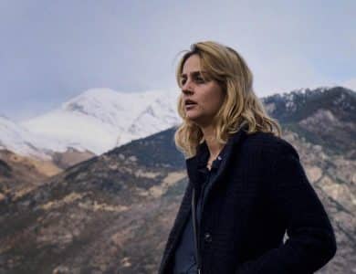 A woman standing in front of a mountain.