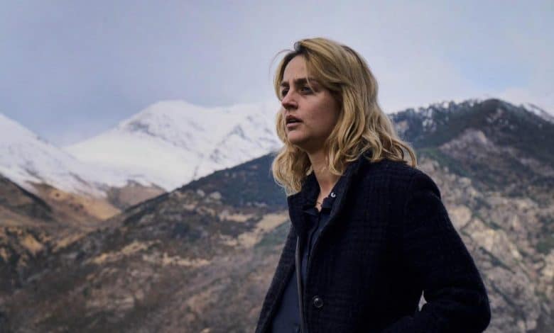 A woman standing in front of a mountain.