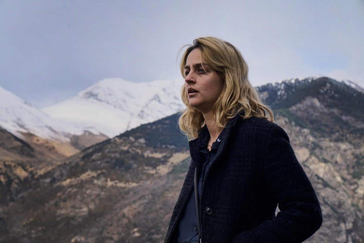 A woman standing in front of a mountain.