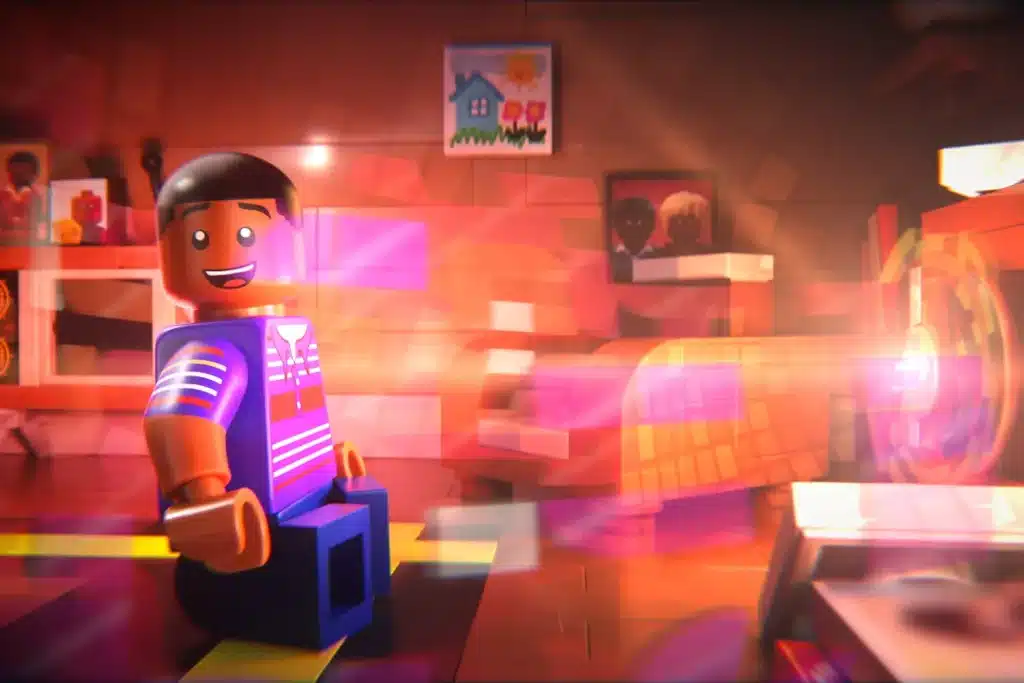 A colorful Lego figure with dark hair and a striped shirt sits in a bright, warmly-lit room. The room features various artwork on the walls, including a painting of a house with flowers and portraits. The scene is artistically blurred with light streaks, adding a dynamic effect to the image.