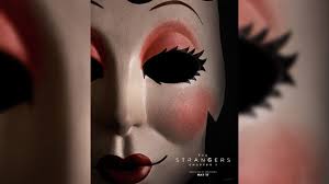 A close-up of a creepy, doll-like mask with exaggerated and dramatic makeup including red lips, rosy cheeks, and dark, hollow eye shapes with long, fake lashes. Text at the bottom reads "The Strangers: Prey at Night" along with a release date of March 9. The background is dark and blurred.