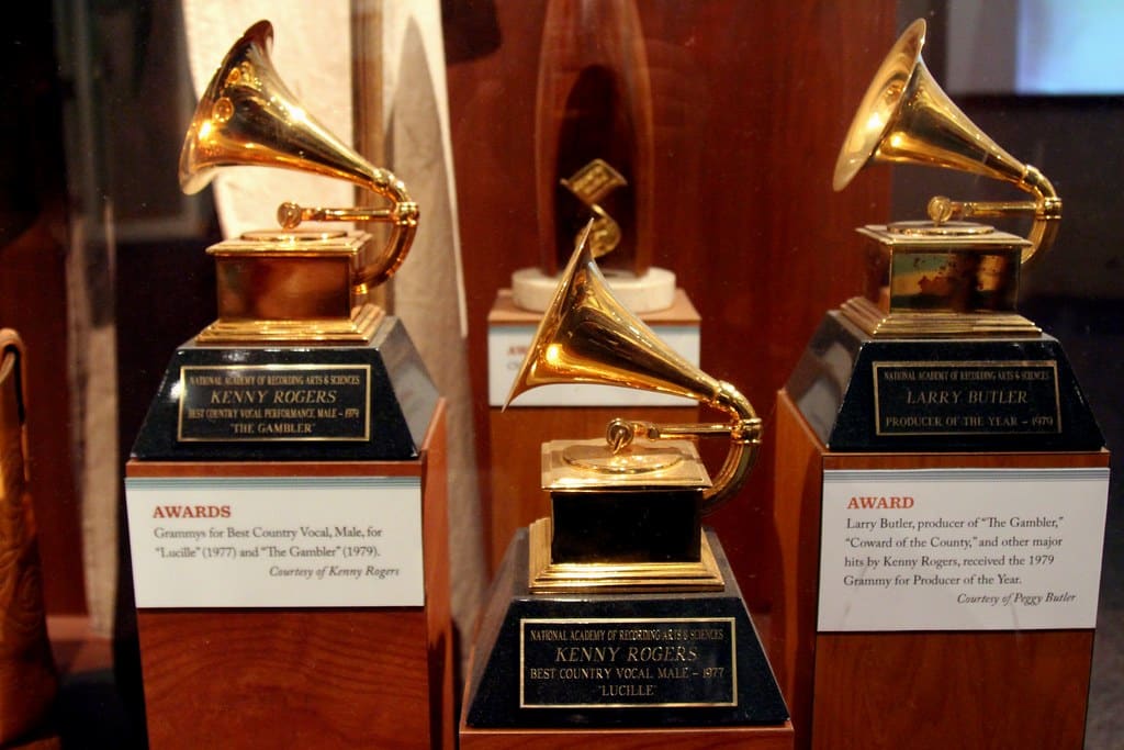 Three Grammy Awards displayed in a case. The plaques read "Kenny Rogers, Best Country Vocal, Male, for 'Lucille' (1977)" and "Larry Butler, Producer of the 'The Gambler', including Best Country Vocal, Male, by Kenny Rogers (1979)." They rest on black bases with gold gramophones.