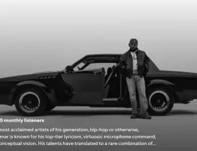 In a black and white image, a man stands by a sleek vintage car with open doors, donning casual attire. A large blue circle announces "#5 in the world," as text below celebrates his GNX album dominating charts, following Kendrick Lamar's triple album record success.